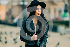 Portrait of young beautiful casual girl in jacket an black hat walking on spring city street.