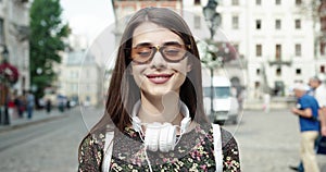 portrait of young beautiful caucasian brown hair woman posing outdoor in the city, looking at camera, pensive - serious