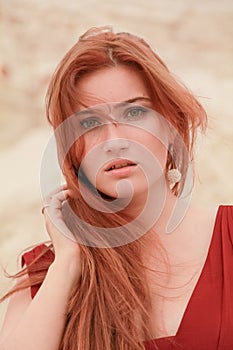 Portrait of Young beautiful Caucasian redheaded woman posing in desert landscape with sand.