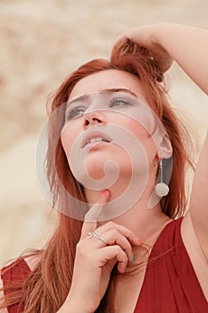 Portrait of Young beautiful Caucasian redheaded woman posing in desert landscape with sand.