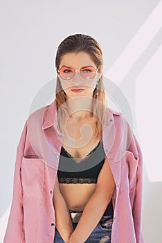 Portrait of young beautiful caucasian woman in dirty pink jacket and eye wear.