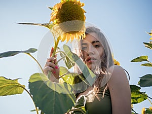 Portrait young beautiful and cheerful woman posing in field of sunflowers at sunset