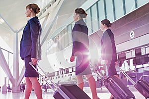 Portrait of young beautiful confident flight attendants walking in airport photo