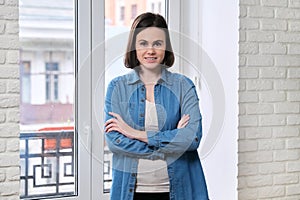 Portrait of young beautiful confident smiling woman in denim shirt with folded arms crossed