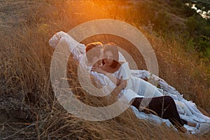 Portrait of a young beautiful couple, a guy and a girl, twenty-two years old. Wearing white clothes. In a grassy field