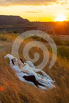 Portrait of a young beautiful couple guy and girl, twenty-two years old. Wearing white clothes. In a grassy field against the