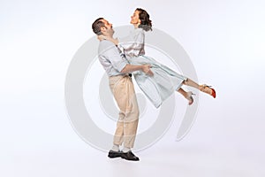 Portrait of young beautiful couple, man and woman, dancing isolated over white studio background. Vintage lifestyle