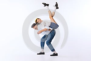 Portrait of young beautiful couple, man and woman, dancing, lifting girl on back isolated over white studio background