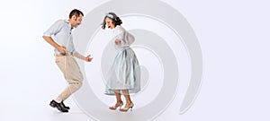 Portrait of young beautiful couple, man and woman, dancing retro dance isolated over white studio background. Cheerful