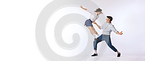 Portrait of young beautiful couple, man and woman, dancing retro dance isolated over white studio background. Lindy Hop