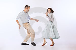 Portrait of young beautiful couple, man and woman, dancing retro dance isolated over white studio background. Romantic