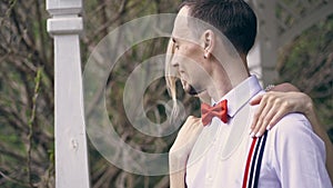 Portrait, young beautiful couple newlyweds hugging, the bride straightens the red bow tie on her fiance. looking at each