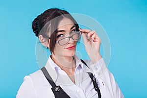 Portrait of young beautiful cute cheerful student girl with glasses smiling looking at camera over blue background.
