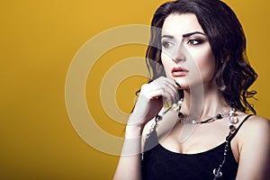 Portrait of a young beautiful dark haired concerned woman wearing black top and glass beads looking worried and thoughtful