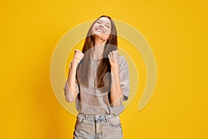 Portrait of young beautiful, emotive girl expressing happiness, success and win against yellow studio background