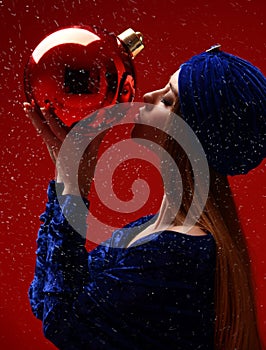 Portrait of young beautiful fashion woman in blue stylish winter dress and hat kissing bug christmas decoration ball