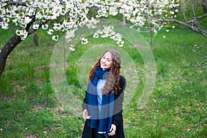 Portrait of a young beautiful fashionable woman in spring blossoming park. Happy girl posing in a blooming garden with white