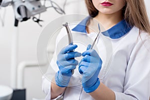 Portrait of young beautiful female dentist holding dental tools at the modern dental office