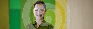 Portrait of a young beautiful female office worker keeping arms crossed, looking at camera and smiling while standing in