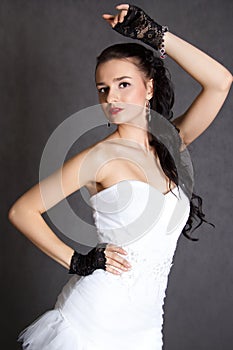 Portrait of a young beautiful fiancee in a wedding dress and black gloves