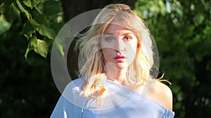 Portrait of a young beautiful girl 21 years old in a blue summer dress. The woman smiles. Beautiful lips and eyes. Long