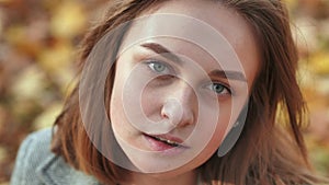 Portrait of a young and beautiful girl against a background of yellow leaves. Face close up.