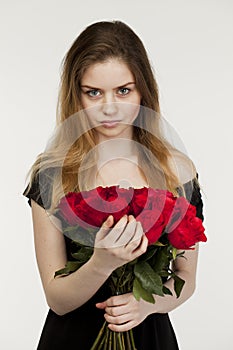 Portrait of a young beautiful girl with a bouquet of red roses