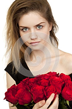 Portrait of a young beautiful girl with a bouquet of red roses