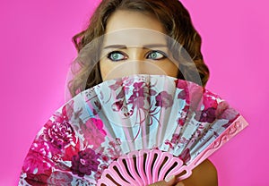 Portrait of a young beautiful girl with bright make-up and a fan in hands close-up on a pink background.