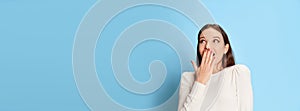 Portrait of young beautiful girl in casual clothes posing with shocked face over blue studio background. Surprise