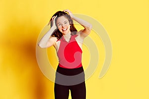 Portrait of young beautiful girl in casual clothes posing with smile against yellow studio background. Positivity and