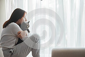 portrait of a young beautiful girl with a cat near the window