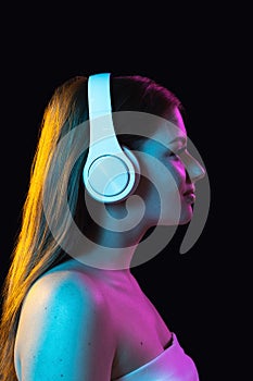 Portrait of young beautiful girl in headphones isolated over dark background.