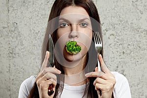 Portrait of a young, beautiful girl holding a broccoli in her mouth.. The concept of a healthy diet, detox, weight loss, diet,