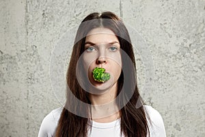 Portrait of a young, beautiful girl holding a broccoli in her mouth.. The concept of a healthy diet, detox, weight loss, diet,