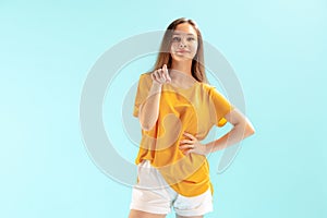 Portrait of young beautiful girl pointing at camera, posing isolated over blue studio background