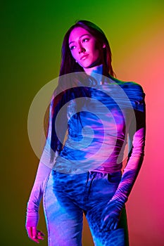 Portrait of young beautiful girl posing against gradient pink green background with neon reflection. Abstract neon art