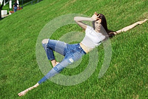 Portrait of a young beautiful girl resting on the lawn in the park