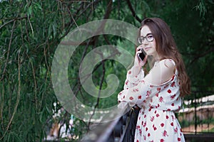 Portrait of a young beautiful girl talking on the phone in the Park