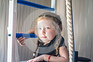 Portrait of young and beautiful gymnast in gymnastic leotard. Little girll goes in for sports on climbing frame. Sports child