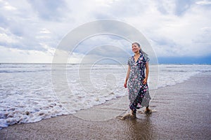 Portrait of young beautiful and happy Asian Chinese woman on her 20s or 30s wearing long chic dress walking alone on beach sea