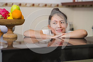 portrait of young beautiful and happy Asian Korean woman posing relaxed at home kitchen cheerful and sweet