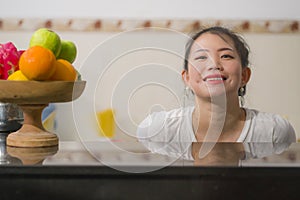 Portrait of young beautiful and happy Asian Korean woman posing relaxed at home kitchen smiling cheerful and sweet