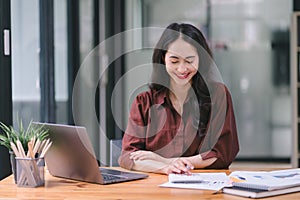 Portrait of young beautiful joyful woman smiling while working with laptop in office.