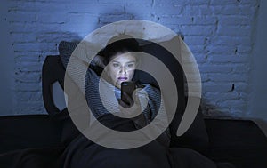 Portrait of young beautiful latin woman using mobile phone late night sleepless lying in bed in the dark in smartphone and interne