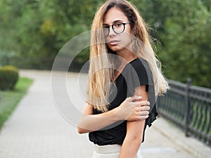 Portrait of young beautiful long hair woman wearing black blouse, holding mobile phone at summer green park path background.