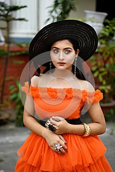 Portrait of young beautiful modern Indian woman wearing western outfit with black straw hat posing fashionable in a blurred