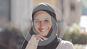 Portrait of young beautiful muslim woman wearing hijab headscarf laughing cheerful in the old city. Close up.