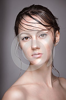 Portrait of young beautiful nude woman with wet shining makeup on grey background