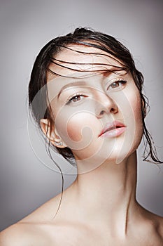 Portrait of young beautiful nude woman with wet shining makeup on grey background